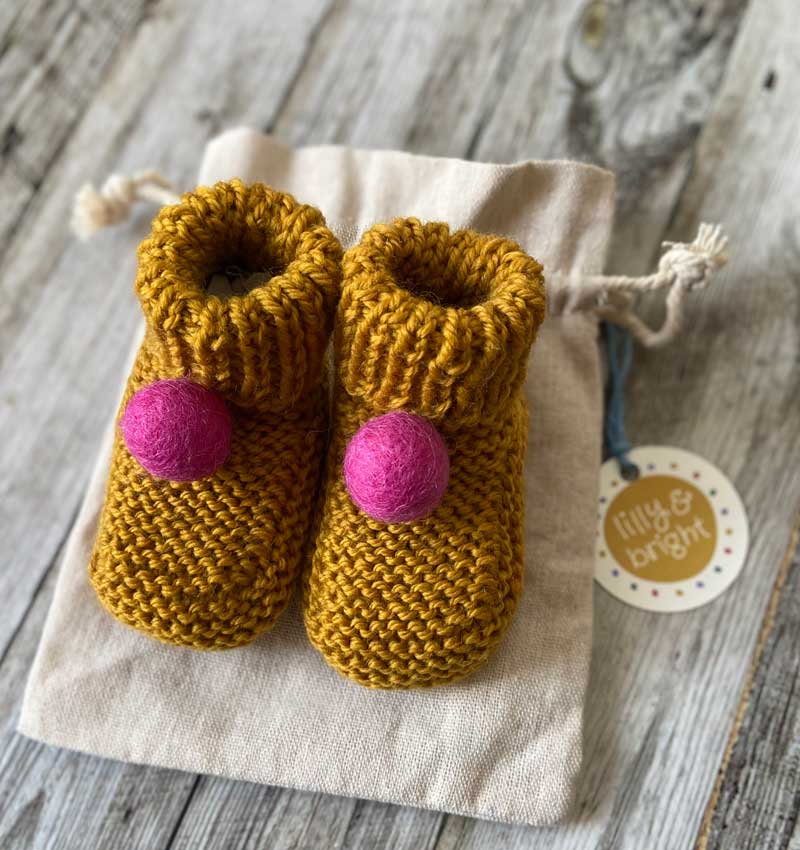 Handknitted Mustard Baby Booties with pink pom pom by Lilly & Bright