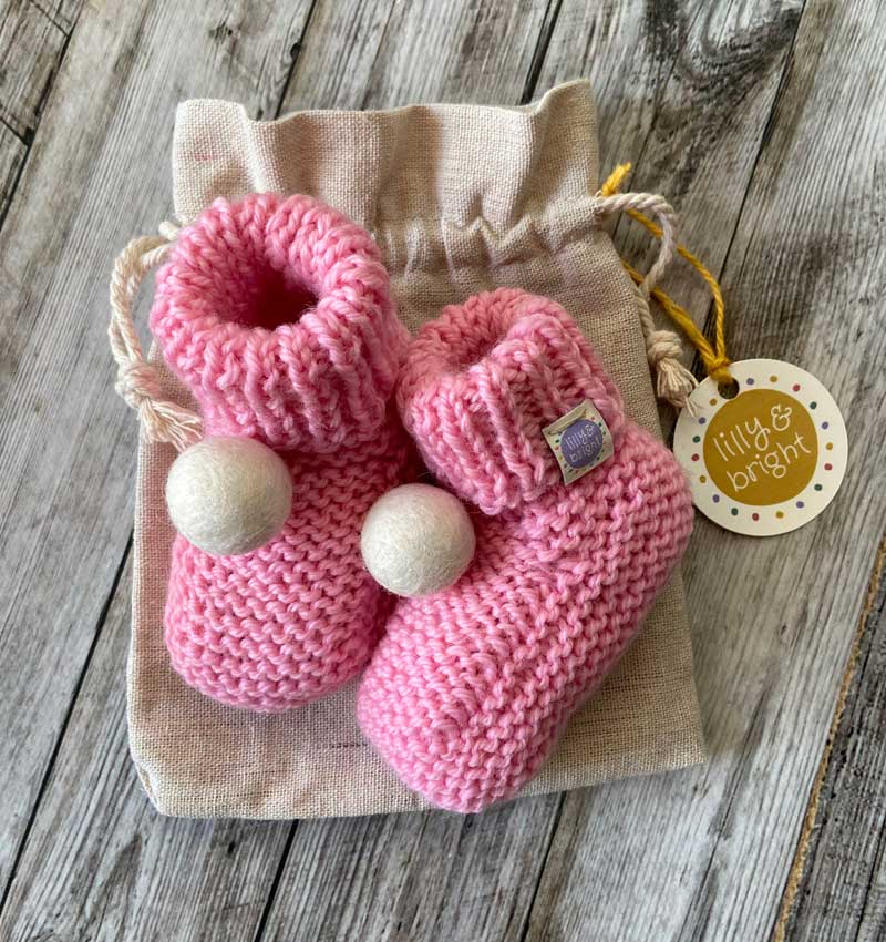 Pink Handknitted Baby Booties with a cream pom pom by Lilly & Bright